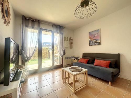 un salon avec un canapé et une télévision dans l'établissement Appartement avec jardin à 30m de la plage, à Villers-sur-Mer