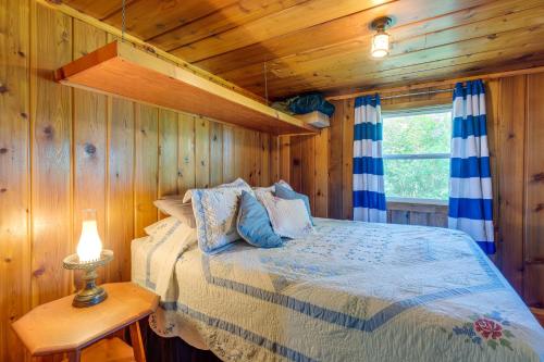 a bedroom with a bed in a wooden cabin at Charming Michigan Cottage with Sunroom and Lake Access in Hubbard Lake