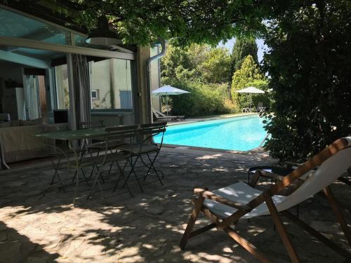 eine Terrasse mit einem Tisch und Stühlen neben einem Pool in der Unterkunft Agréable maison de 65 m2 avec grande piscine in Aix-en-Provence
