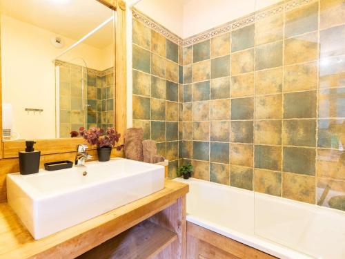 La salle de bains est pourvue d'un lavabo blanc et d'une baignoire. dans l'établissement Appartement de prestige en hyper centre avec piscine, sauna et parking sécurisé - FR-1-296-422, à Saint-Lary-Soulan