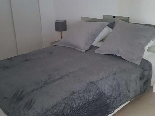une chambre avec un grand lit avec des draps et des oreillers gris dans l'établissement Villeneuve-Loubet : Appartement avec Terrasse, Climatisation et Garage - FR-1-252A-34, à Villeneuve-Loubet