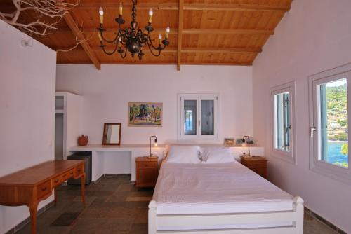 a bedroom with a bed and a desk and windows at Kavos Villa in Aghios Petros Alonissos