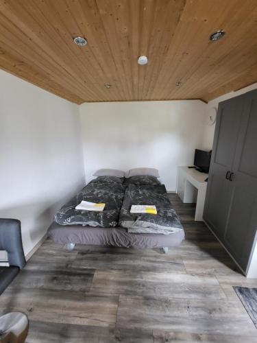 a bed in a small room with a wooden ceiling at Das blaue Häusle in Hofe