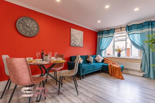 a living room with a couch and a clock on the wall at Rush House by SR Short Lets & Serviced Accommodation Heathrow Windsor - Perfect for Monthly Stay Relocation & Business Contractors Big Groups in Northolt