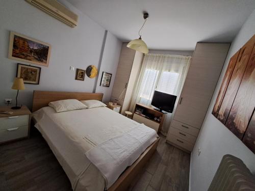 um pequeno quarto com uma cama e uma televisão em Elegant house near the sea em Artemida