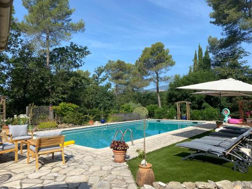 een zwembad met stoelen en een parasol ernaast bij Maison agréable et familliale in Roquefort-les-Pins