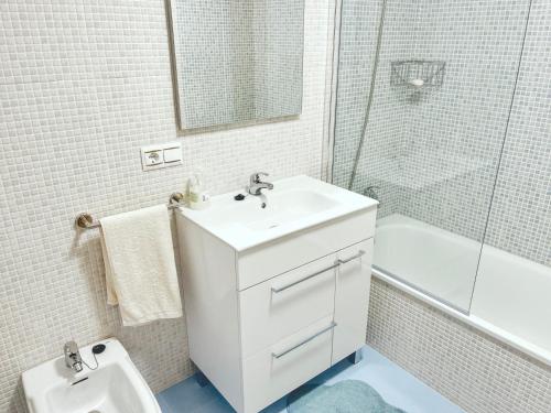 a white bathroom with a sink and a toilet at Ático Pampaído in Raxo