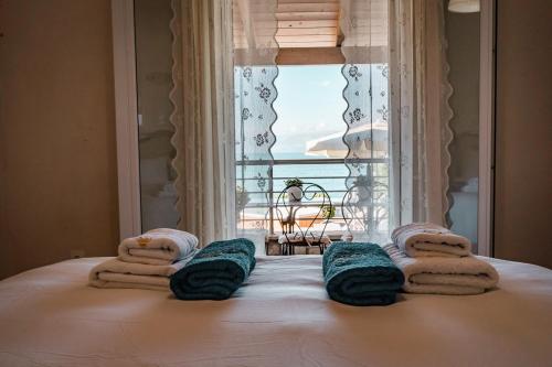 a bedroom with a bed with towels and a window at Neptune Sea House - Beachfront in St. Spyridon Corfu