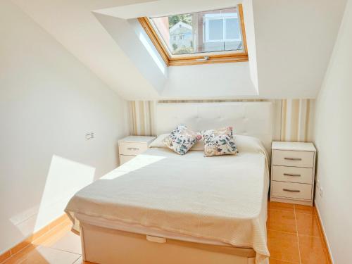 a small bedroom with a bed and a skylight at Ático Pampaído in Raxó