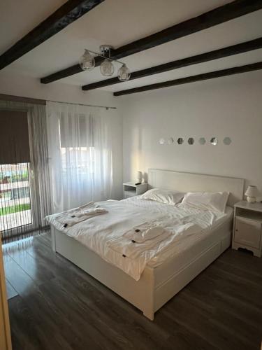 a white bedroom with a large bed and a window at House Of Beyoutiful Bocsa in Bocşa