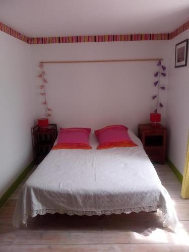 ein Schlafzimmer mit einem weißen Bett mit zwei roten Kissen in der Unterkunft chez Florence, chambres d'hôtes , Montrol Sénard 