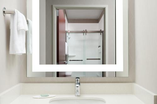 a bathroom with a mirror over a sink at SpringHill Suites Kansas City Overland Park in Overland Park