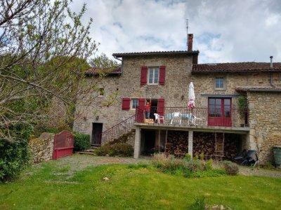 a large stone house with red doors and a balcony at chez Florence, chambres d'hôtes , Montrol Sénard in Montrol-Sénard