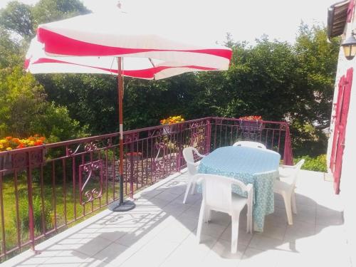 einen Tisch, Stühle und einen Regenschirm auf einer Terrasse in der Unterkunft chez Florence, chambres d'hôtes , Montrol Sénard 