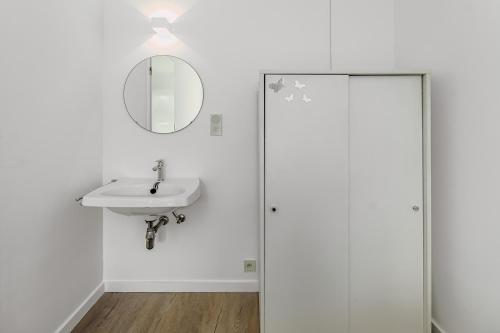 Baño blanco con lavabo y espejo en Boreas Sunrise GV04, en Koksijde