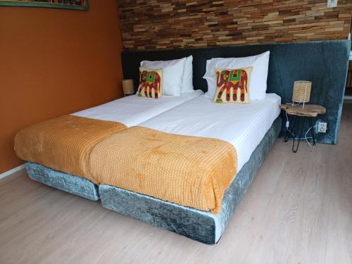 a bedroom with two twin beds with pillows and a brick wall at East Meets West Bed and Breakfast in Veenendaal