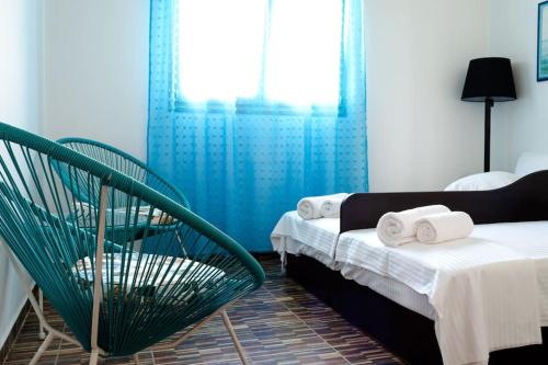 a bedroom with two beds and a green chair at Maria’s Sunset House in Megalochori