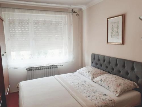 1 dormitorio con 1 cama con ventana y colcha en Spacious 80m2 Apartment in the Center en Ljubuški