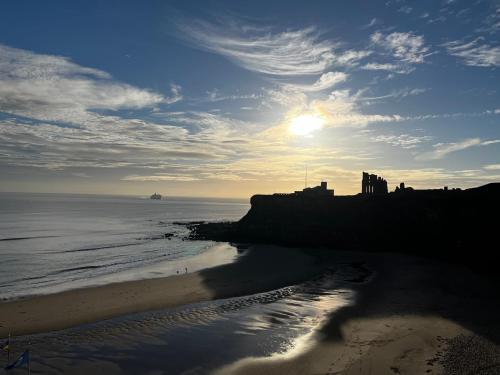 a beach with the sun rising over the ocean at Village view apartments in Tynemouth