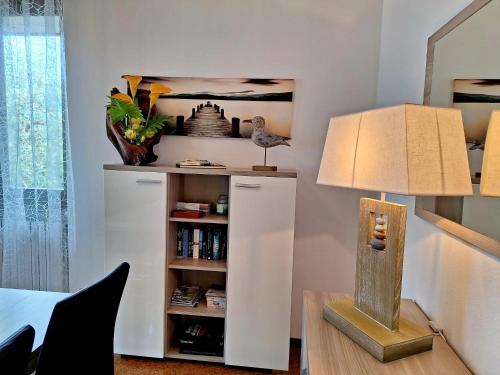 a room with a book shelf and a lamp on a table at Le Grigne Guest House in Oliveto Lario