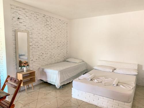 two beds in a white room with a mirror at Pousada La Goduria in Canoa Quebrada