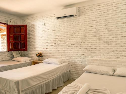 a room with two beds and a brick wall at Pousada La Goduria in Canoa Quebrada