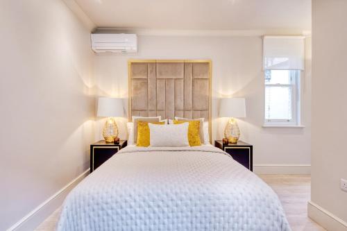 Marble Arch Suite 3-Hosted by Sweetstay في لندن: غرفة نوم بيضاء بسرير كبير ومصباحين