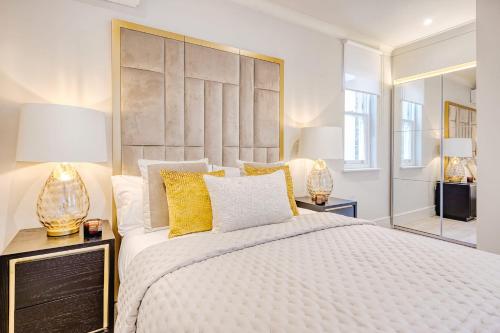 Marble Arch Suite 3-Hosted by Sweetstay في لندن: غرفة نوم بسرير كبير مع مخدات صفراء