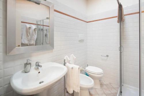 a white bathroom with a sink and a toilet at La Casina apartament in Ferrara
