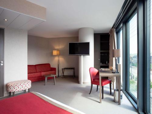 a living room with a red couch and a red chair at Mercure Clermont Ferrand centre Jaude in Clermont-Ferrand