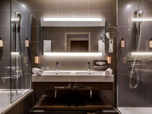 W łazience znajduje się umywalka i lustro. w obiekcie Mercure Clermont Ferrand centre Jaude w mieście Clermont-Ferrand
