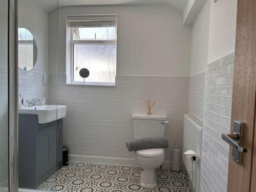 a bathroom with a toilet and a sink and a window at Mona Lodge - 3 bed cottage in Llandudno in Llandudno