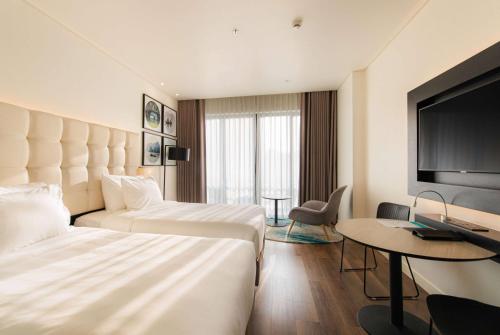 a hotel room with two beds and a flat screen tv at Hotel Soleil Ha Long, Trademark Collection by Wyndham in Ha Long