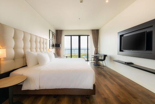 a bedroom with a large white bed and a flat screen tv at Hotel Soleil Ha Long, Trademark Collection by Wyndham in Ha Long