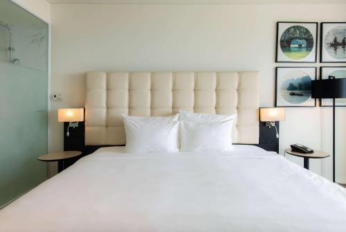 a bedroom with a large white bed with two lamps at Hotel Soleil Ha Long, Trademark Collection by Wyndham in Ha Long