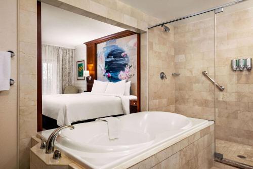 ein Badezimmer mit einer Badewanne und ein Schlafzimmer mit einem Bett in der Unterkunft Viana Hotel and Spa, Trademark Collection by Wyndham in Westbury