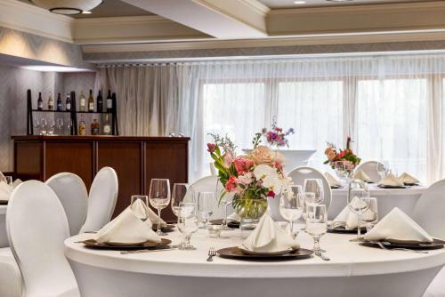 a dining room with a white table and white chairs at Viana Hotel and Spa, Trademark Collection by Wyndham in Westbury