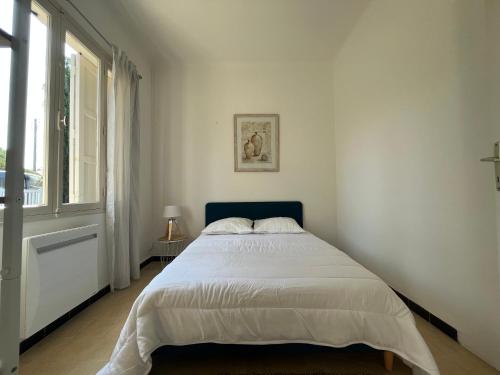 une chambre blanche avec un grand lit et une fenêtre dans l'établissement CAPELAN, à Bandol