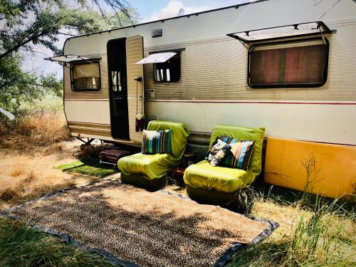 an rv with two green chairs and a trailer at Caravan on the beach, pet friendly in Corbu