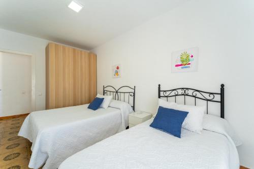 2 camas en una habitación con sábanas blancas y almohadas azules en Apartamento Estudio Acuario Frente Mar, en Barbate