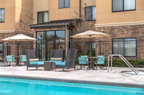 a pool with chairs and umbrellas next to a building at Residence Inn by Marriott Los Angeles Redondo Beach in Redondo Beach