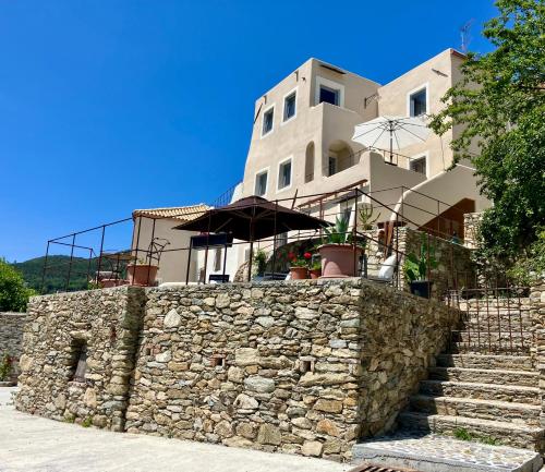 a building behind a stone wall with stairs and an umbrella at Il Contado in Noli