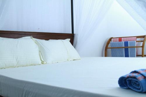 a white bed with a wooden headboard and white pillows at A2+villa in Weligama