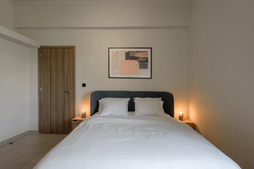 a bedroom with a large white bed with two candles at Galio Suites Airport by Airstay in Spata