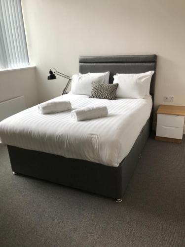 een slaapkamer met een groot bed met witte lakens en kussens bij Quality City Birmingham in Birmingham