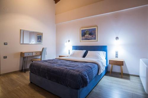 a bedroom with a bed with a blue bedspread and a table at Modern, Stylish Maisonette in Itea