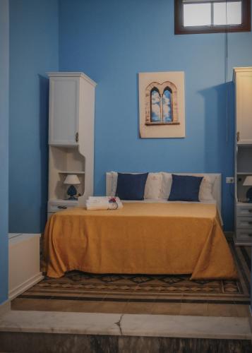 a blue bedroom with a bed with an orange blanket at La Bifora e il granaio in Sciacca
