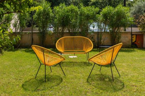 three yellow chairs and a table in the grass at Osvaldo - parcheggio e giardino privato in San Giovanni in Persiceto