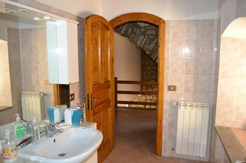 ein Badezimmer mit einem Waschbecken und einer Holztür in der Unterkunft Cilento Stone House in San Mauro Cilento