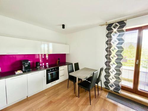 una cocina con armarios blancos y una mesa con sillas. en Apartament Studio Platan en Świnoujście